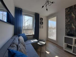 a living room with a blue couch and two windows at Komfortowy apartament z balkonem i parkingiem in Wrocław