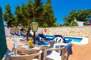 a patio with tables and chairs next to a swimming pool at Villa Casa Blanca by Villa Plus in Cala Blanca