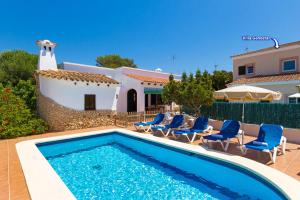 a swimming pool with chairs and a house at Villa Casa Blanca by Villa Plus in Cala Blanca