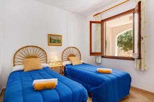 two blue beds in a room with a window at Villa Casa Blanca by Villa Plus in Cala Blanca