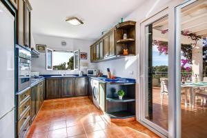 uma cozinha com armários de madeira e uma mesa de jantar em Villa Tama by Villa Plus em Sant Lluis