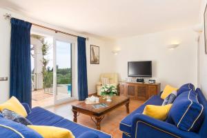uma sala de estar com um sofá azul e uma televisão em Villa Tama by Villa Plus em Sant Lluis