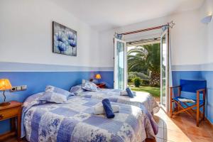 um quarto azul com 2 camas e uma porta de vidro deslizante em Villa Tama by Villa Plus em Sant Lluis