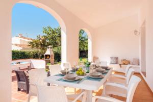 una sala da pranzo bianca con tavolo e sedie di Villa Adelaide by Villa Plus a Sant Lluís