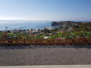 a wooden bench sitting on a hill overlooking the ocean at KIRA'S RESIDENCE PANORAMIC VIEW in Archangelos