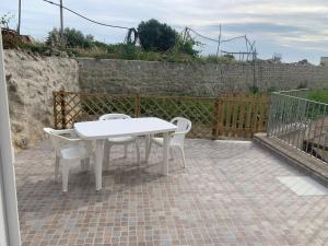 einen weißen Tisch und Stühle auf einer Backsteinterrasse in der Unterkunft Residence Andrea a mare in Ischia