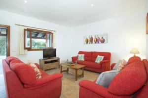 ein Wohnzimmer mit 2 roten Stühlen und einem TV in der Unterkunft Villa Sol Pollensa by Villa Plus in El Port
