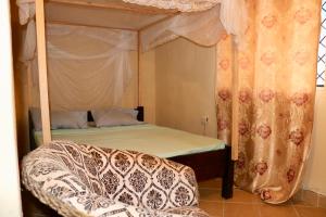 a bedroom with a four poster bed with a canopy at 4 Bed Villa - Sleeps 8 - Pool - Garden - Parking in Diani Beach +2 photos