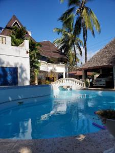 a swimming pool with a bridge and palm trees at Lovely 4-Bed Villa Family oriented or a smallgroup in Diani Beach