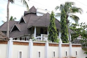 a house with a black roof and palm trees at 4 Bed Villa - Sleeps 8 - Pool - Garden - Parking in Diani Beach