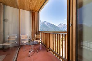 a balcony with a table and chairs and a large window at Chasa Laina in Sent