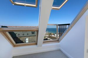 a room with a balcony with a view of the ocean at Trevail Penthouse in St Ives