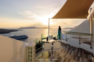 Una donna in piedi su un balcone che guarda l'oceano di Fira Deep Blue Suites a Firà