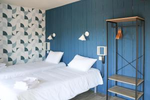 two beds in a room with blue walls at Mon P'tit Hôtel in Le Grau-dʼAgde