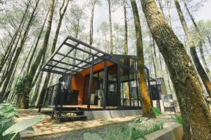 a glass house in a forest with trees at Bobocabin Cikole, Bandung in Lembang