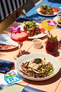 a table topped with plates of food on top of a wooden table at Mama Shelter Los Angeles in Los Angeles