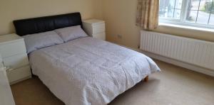 a bedroom with a bed with a black headboard and a window at Lovely 2-Bedroom New Forest apartment on a Farm in New Milton
