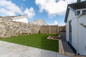 a garden with a stone wall and a lawn at Chi Lowen in Carbis Bay