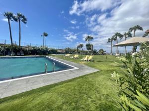 サンミゲル・デ・アボナにあるPrime Homes- San Miguel Golf,Ocean Front Bungalowのヤシの木と芝生のあるスイミングプール