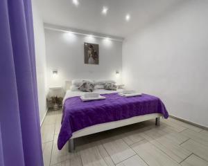 a bedroom with a purple bed with towels on it at Apartment Pink in Split