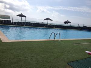 una gran piscina con sombrillas en el césped en MAGNIFICO ATICO-DUPLEX FRENTE AL MAR, en El Puig