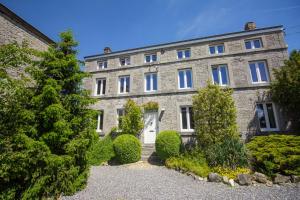 a large stone building with a white door at Relax à Maison Sax Kingsize in Durbuy