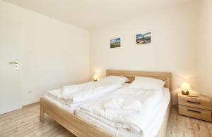 a bedroom with a bed with white sheets and pillows at Küstenperle - 3 in Cuxhaven