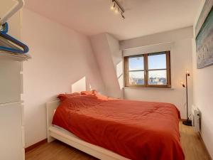 a bedroom with a red bed with a window at Comfortabel Gezinsappartement 'Emmy' te Oostduinkerke in Oostduinkerke