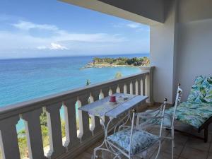 einen Balkon mit einem Tisch, Stühlen und Meerblick in der Unterkunft Deep Blue Villas in Vasilikos