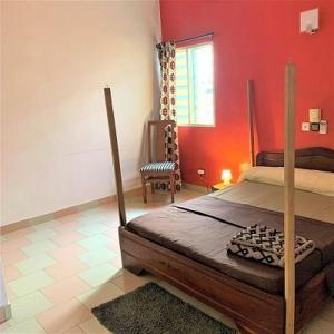 een slaapkamer met een bed en een rode muur bij COSY APPARTEMENT MEUBLE & BIEN EQUIPE in Cotonou