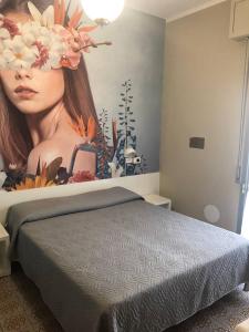 1 dormitorio con 1 cama y una pintura de una mujer en Hotel Wega, en Bellaria-Igea Marina