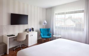 Habitación de hotel con cama, escritorio y TV. en NH Madrid Ventas en Madrid