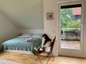 ein Schlafzimmer mit einem Bett und einem Stuhl neben einem Fenster in der Unterkunft Hahnenklee Charme - moderne neue Ferienwohnung mit 2 Balkons in Hahnenklee-Bockswiese