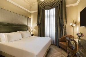 a hotel room with a bed and a chair and a window at NH Collection Carlo IV in Prague