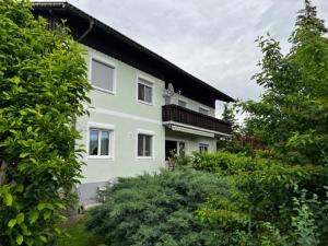 una casa blanca con techo negro y algunos árboles en Ferienwohnung Rohrmeister, en Eberndorf