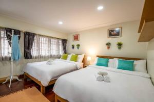 AT NANA-5Bed, CITY CENTER, Nana BTS, MBK, Central World, Siam في بانكوك: سريرين في غرفة خضراء وبيضاء