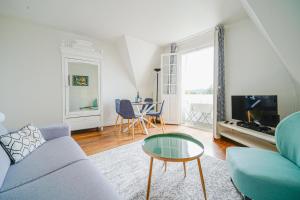 ein Wohnzimmer mit einem blauen Sofa und einem Tisch in der Unterkunft Le Manoir du Vert Galant in Deauville