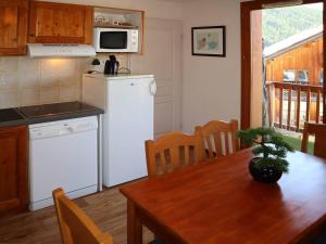 a kitchen with a table and a white refrigerator at Appartement Les Orres, 2 pièces, 6 personnes - FR-1-322-423 in Les Orres