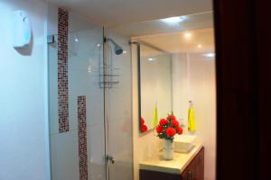 a bathroom with a shower and a vase of red flowers at Casa Marqués del Pedregal in Cartagena de Indias