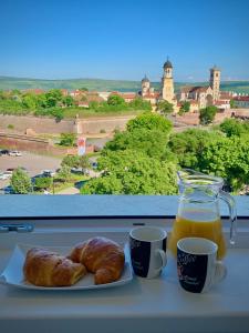 un plato de cruasanes y una jarra de zumo de naranja y dos tazas en Citadel Residence, en Alba Iulia