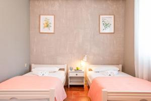 two beds in a room with pink sheets at Dimitra's Garden - Holiday Apartments in Parga