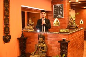 a man in a suit and tie standing behind a counter at Sacred Boutique Hotel in Kathmandu