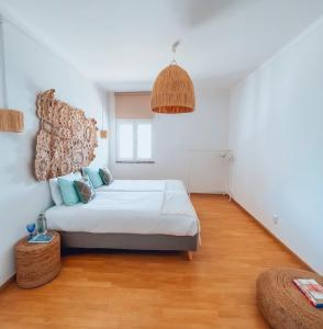 a white bedroom with a bed and a wooden floor at Maison Comporta in Comporta