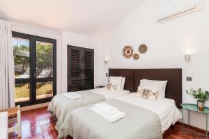 twee bedden in een witte kamer met een raam bij Casas Barulho - Villa Jacaranda A8 in Albufeira