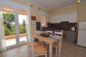 a kitchen with a table with chairs and a refrigerator at Ykies Apartment by Corfuescapes in Kanoni