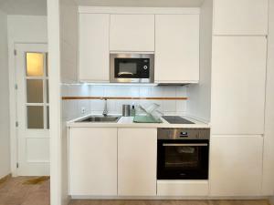 a white kitchen with a sink and a microwave at Magnífico apartamento con excelente ubicación in Don Benito