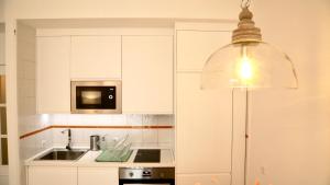 cocina blanca con fregadero y microondas en Magnífico apartamento con excelente ubicación en Don Benito