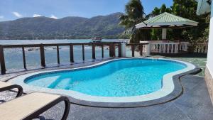 a swimming pool with a view of the water at Drake Seaside Studio Apartments in Bel Ombre