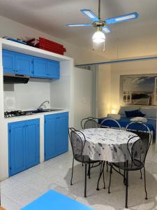 a kitchen with blue cabinets and a table with chairs at Casa Vacanze Casti - 41 in Calasetta