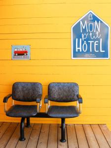 two chairs in front of a yellow wall with a sign at Mon P'tit Hôtel in Le Grau-dʼAgde